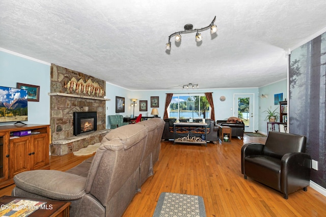 living area with a textured ceiling, wood finished floors, and a stone fireplace