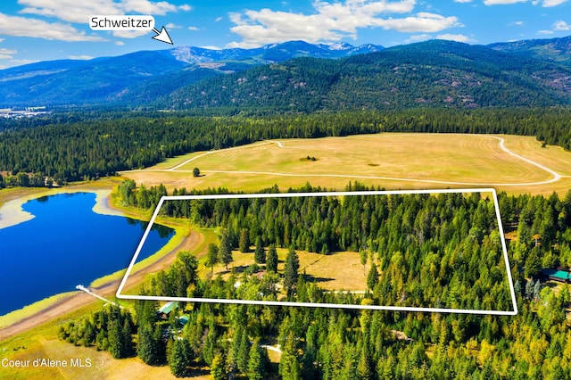 aerial view featuring a wooded view and a water and mountain view