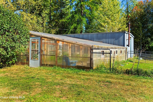 view of greenhouse featuring a lawn and fence