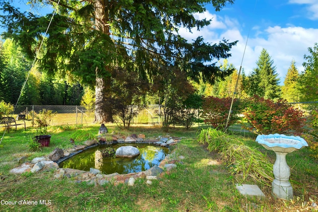 view of yard featuring a small pond and fence