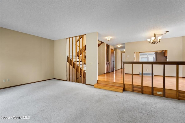 spare room featuring a chandelier, stairs, carpet flooring, and visible vents