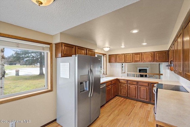 kitchen with appliances with stainless steel finishes, brown cabinets, and light countertops