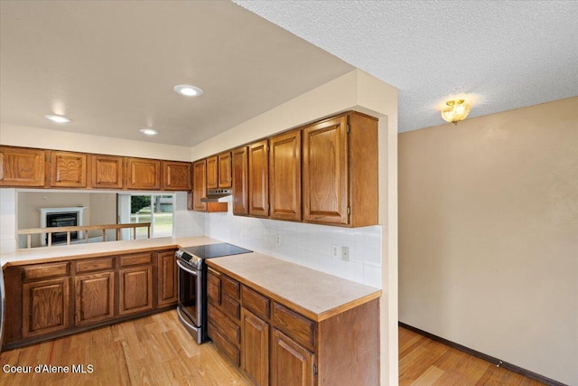 kitchen featuring brown cabinets, light wood-style floors, light countertops, and electric stove