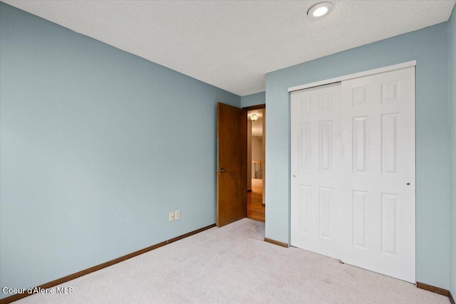 unfurnished bedroom with a textured ceiling, a closet, carpet flooring, and baseboards