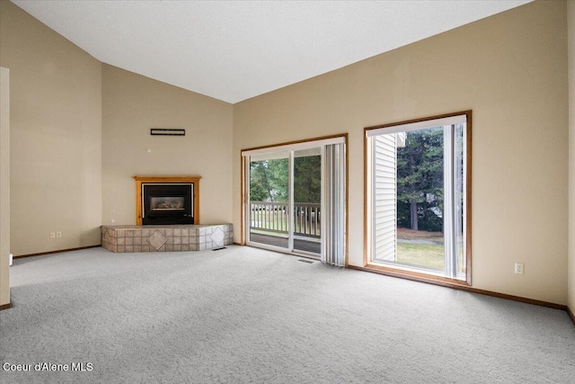 unfurnished living room with high vaulted ceiling, a tile fireplace, carpet flooring, and baseboards