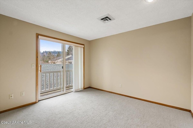 carpeted spare room with visible vents, a textured ceiling, and baseboards