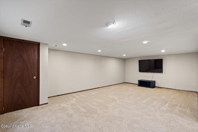 finished below grade area featuring a textured ceiling, carpet, baseboards, and recessed lighting