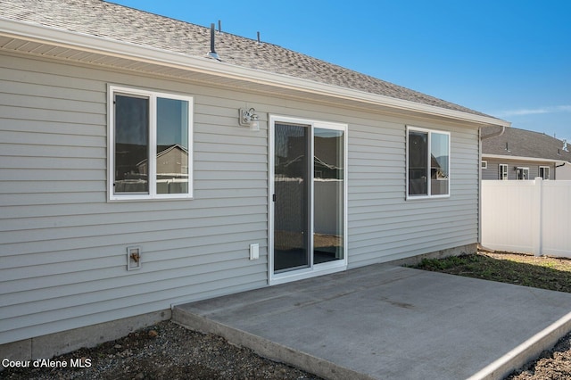 back of house featuring a patio, a shingled roof, and fence