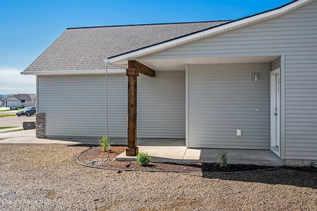 view of side of home with roof with shingles