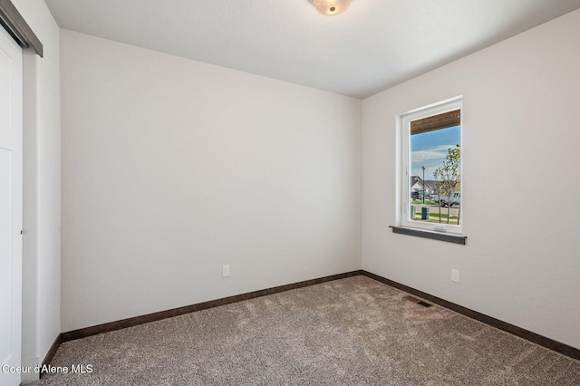 empty room with carpet floors, visible vents, and baseboards