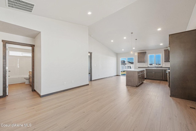 kitchen with dark brown cabinetry, visible vents, light countertops, a center island, and light wood finished floors