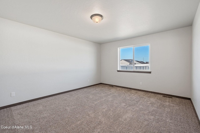 unfurnished room with carpet flooring, visible vents, and baseboards