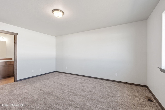 empty room with baseboards, visible vents, and light colored carpet