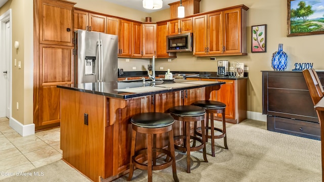 kitchen with appliances with stainless steel finishes, dark countertops, brown cabinets, and light tile patterned flooring