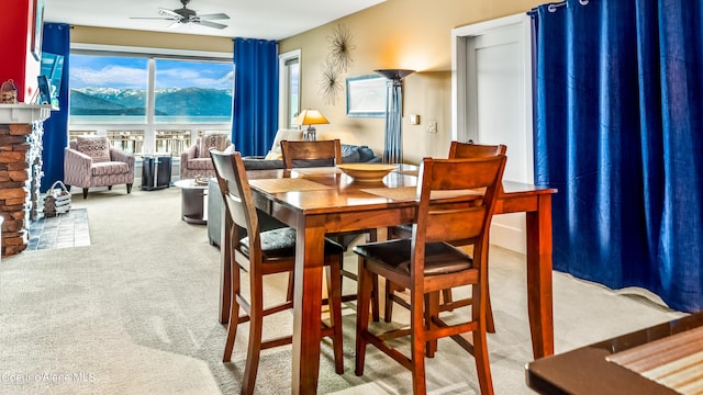 dining area with a water and mountain view, carpet, and a ceiling fan