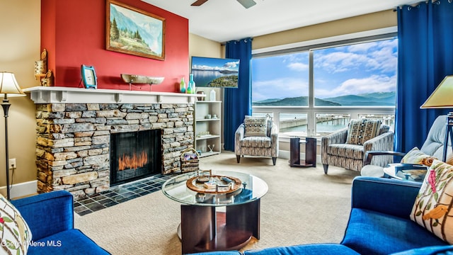 carpeted living room featuring a fireplace and a ceiling fan