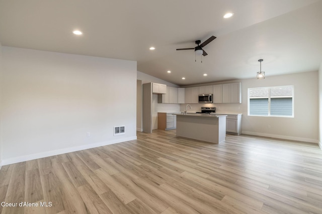 kitchen with ceiling fan, appliances with stainless steel finishes, open floor plan, vaulted ceiling, and a sink