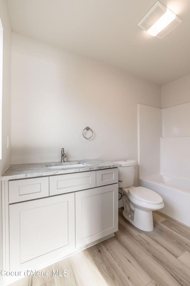 bathroom featuring visible vents, toilet, tub / shower combination, vanity, and wood finished floors