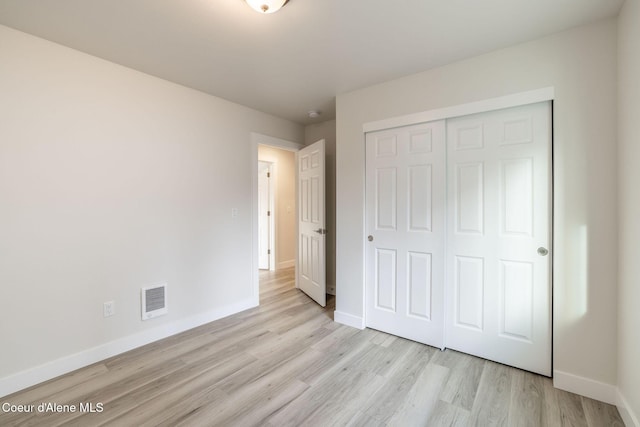 unfurnished bedroom with a closet, light wood-type flooring, visible vents, and baseboards