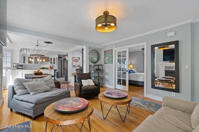 living area featuring ornamental molding, light wood-type flooring, a chandelier, and a fireplace