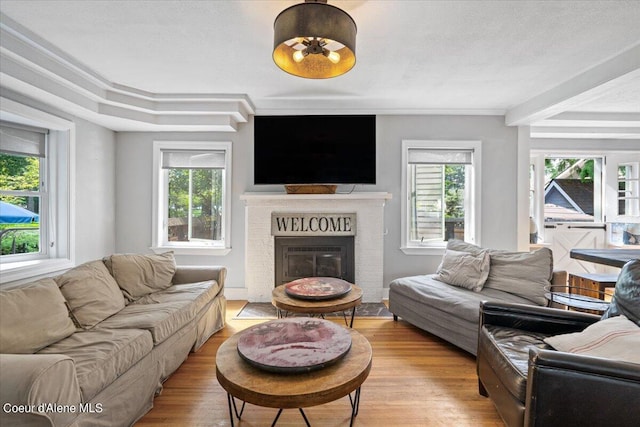 living room with light wood-style floors, a wealth of natural light, a brick fireplace, and a textured ceiling