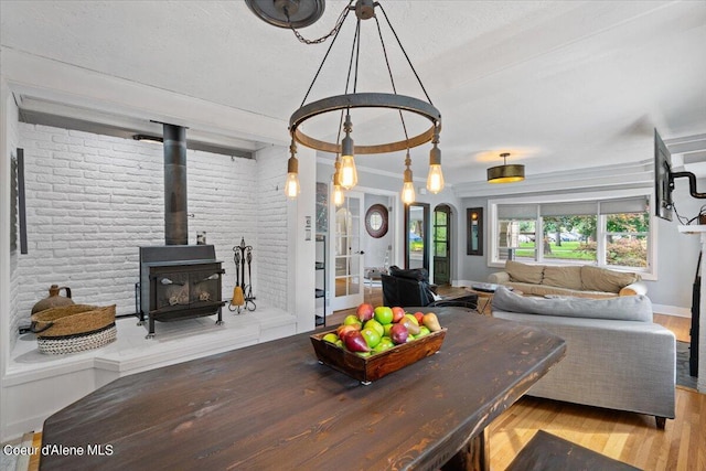 dining room with a wood stove, brick wall, baseboards, and wood finished floors