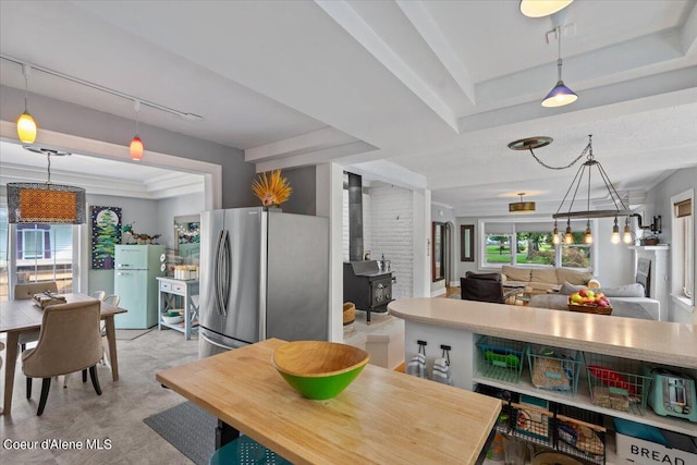 kitchen featuring track lighting, freestanding refrigerator, a tray ceiling, a wood stove, and pendant lighting