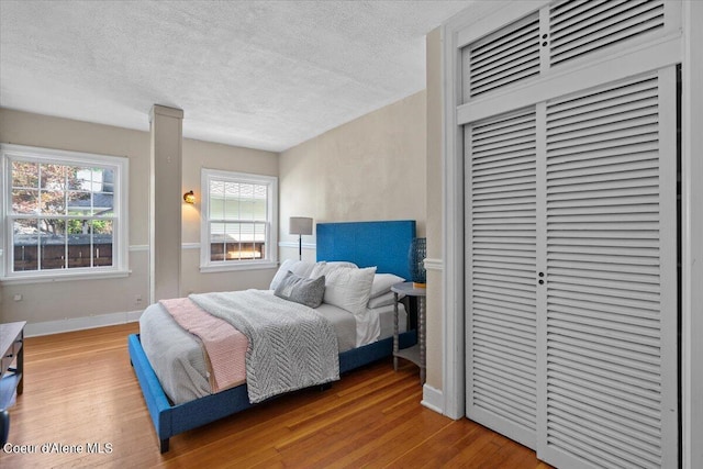 bedroom featuring a textured ceiling, a closet, a heating unit, and wood finished floors