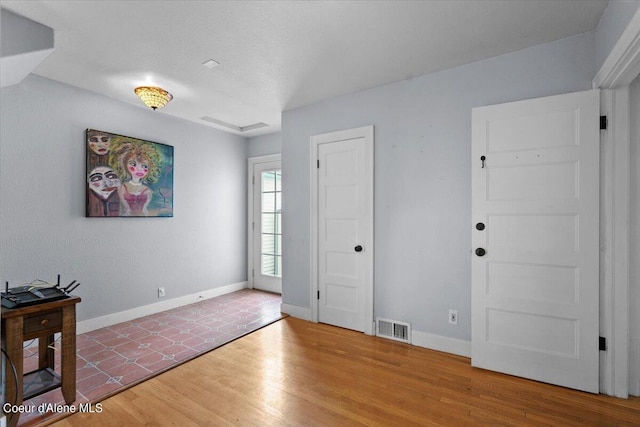 foyer entrance featuring wood finished floors, visible vents, and baseboards