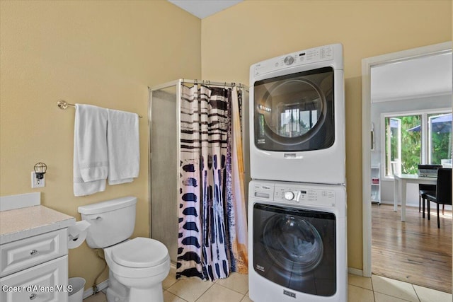 washroom with light tile patterned floors, laundry area, baseboards, and stacked washer / drying machine