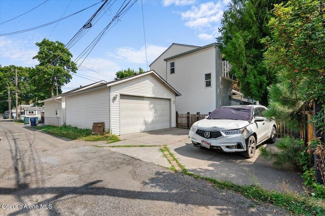 view of side of home featuring a garage, fence, and an outbuilding