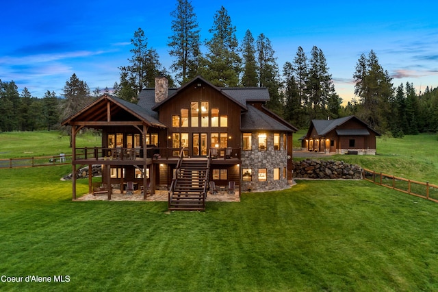 back of property with a chimney, a lawn, fence, a wooden deck, and stairs