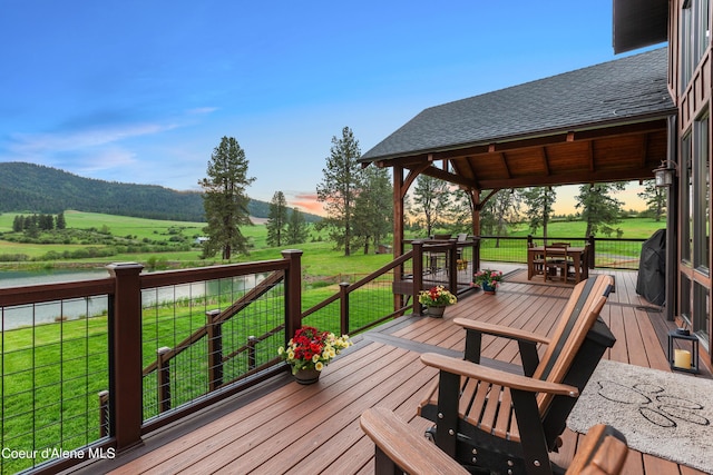 wooden terrace with a rural view and a yard