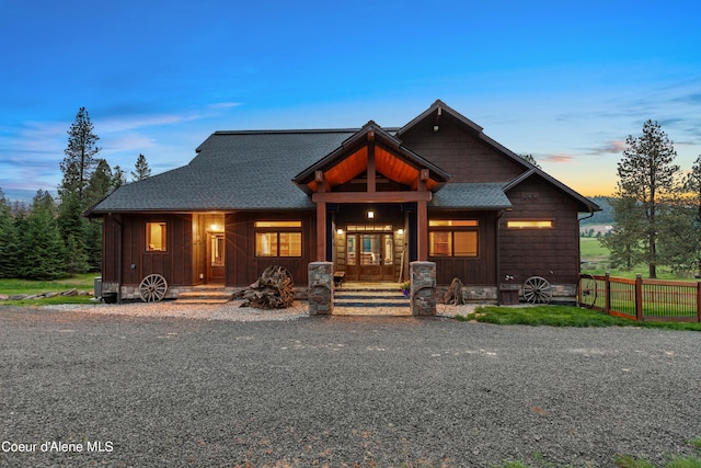 view of front facade with roof with shingles, board and batten siding, and fence