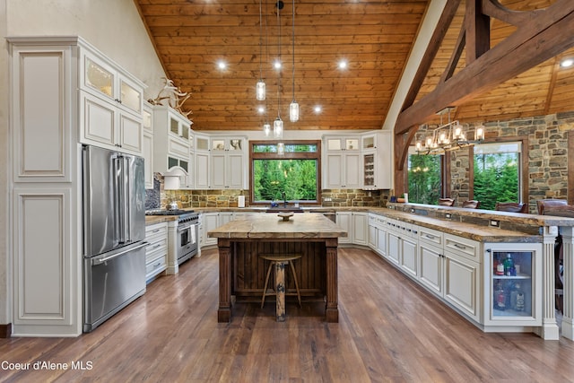 kitchen with stainless steel appliances, a peninsula, a kitchen island, decorative backsplash, and dark wood-style floors