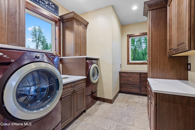 laundry area featuring cabinet space, stone finish flooring, baseboards, and washing machine and clothes dryer