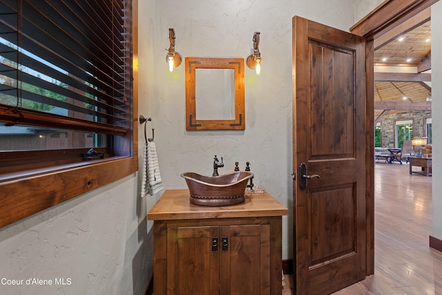 bathroom with a textured wall, vanity, and wood finished floors