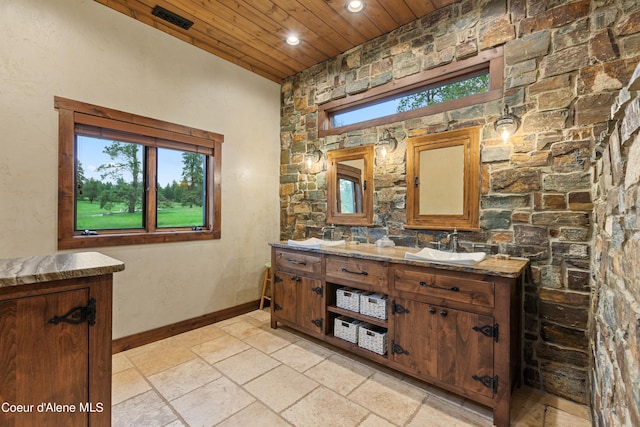 full bathroom featuring double vanity, wood ceiling, baseboards, and stone tile flooring