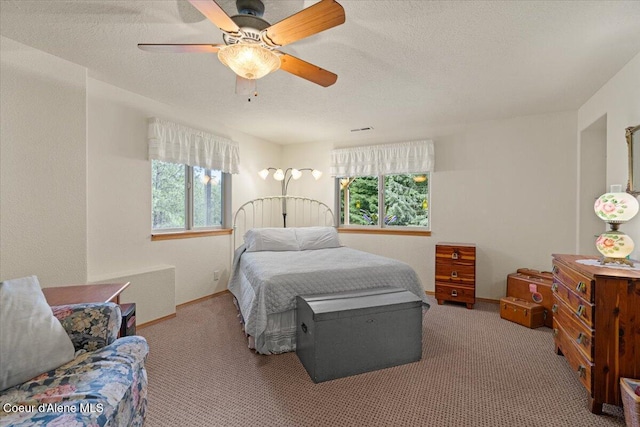 carpeted bedroom featuring visible vents, multiple windows, ceiling fan, and a textured ceiling