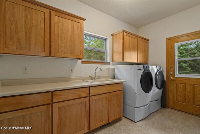 laundry room with cabinet space, light floors, a sink, and washing machine and clothes dryer