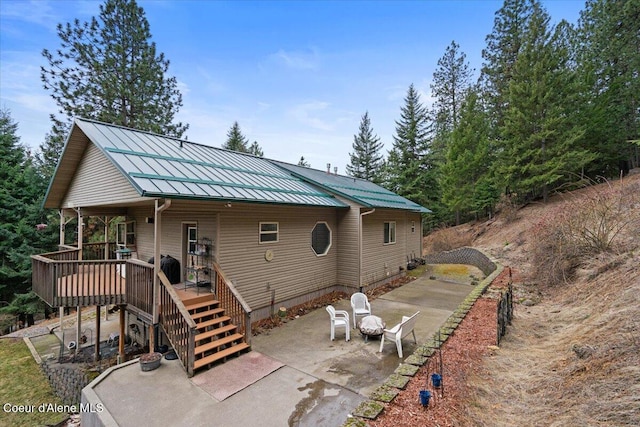 view of front of property featuring a deck, metal roof, stairs, a standing seam roof, and a patio area