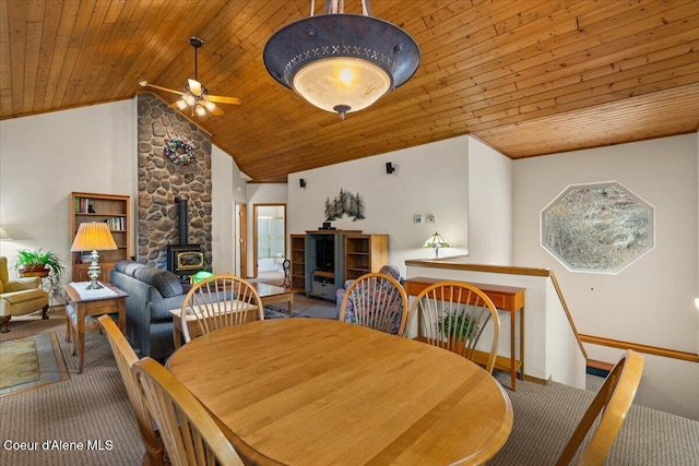 dining room with ceiling fan, a wood stove, carpet floors, and wood ceiling