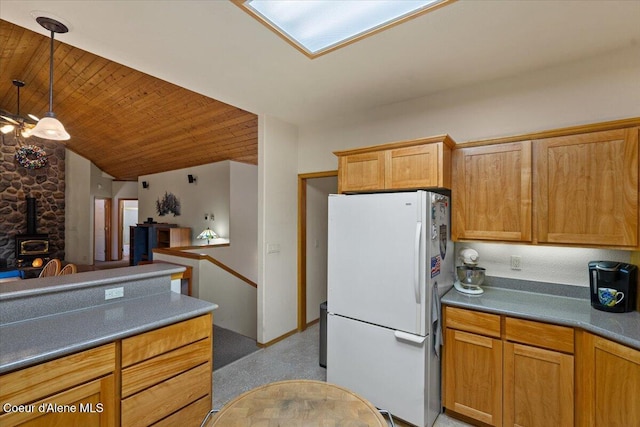 kitchen with a wood stove, dark countertops, wood ceiling, and freestanding refrigerator