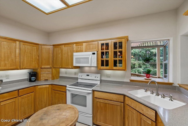 kitchen with white appliances, glass insert cabinets, light countertops, and a sink