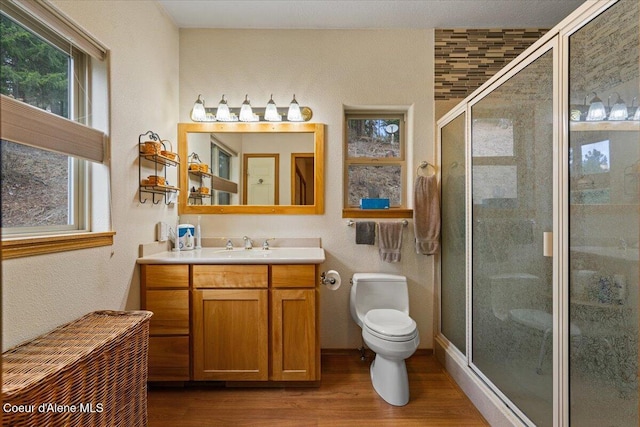 full bath with vanity, a stall shower, wood finished floors, and toilet