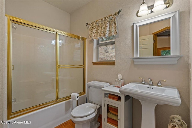 bathroom featuring toilet and combined bath / shower with glass door