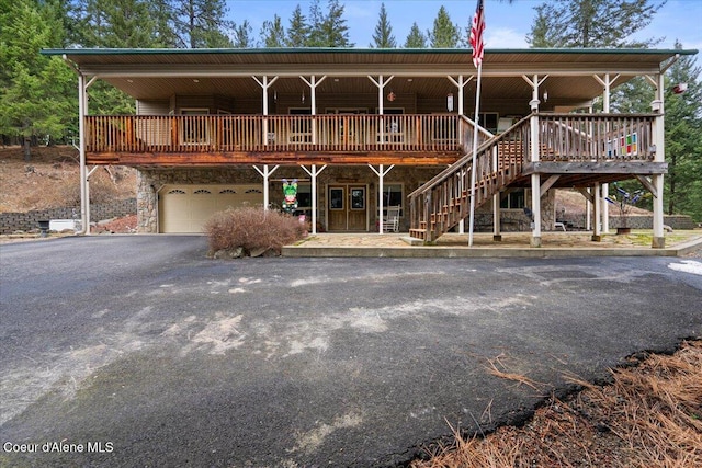 view of front facade featuring a garage, stone siding, aphalt driveway, and stairway