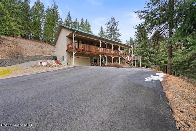 rustic home with aphalt driveway, cooling unit, a garage, and stairs