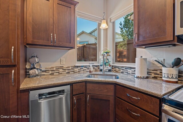 kitchen with a sink, stainless steel appliances, light stone countertops, and tasteful backsplash