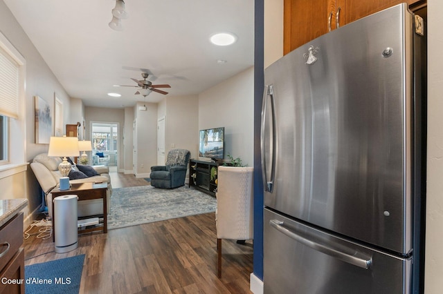 kitchen with a ceiling fan, freestanding refrigerator, brown cabinetry, baseboards, and dark wood-style flooring